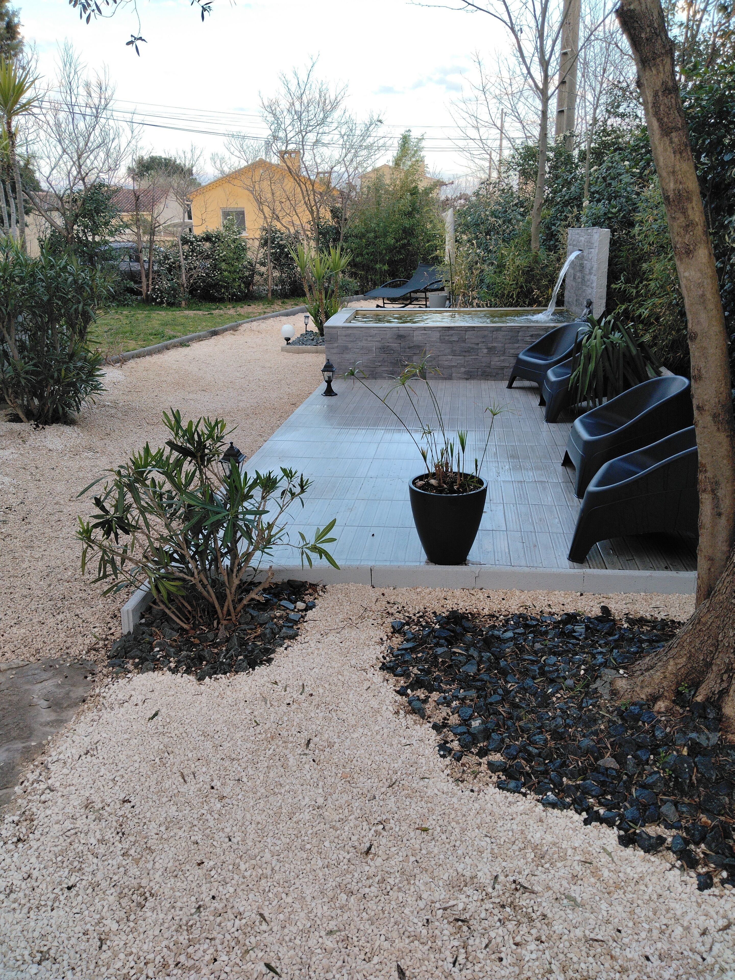 Un patio con piscina, mobiliario y plantas en macetas.
