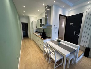 A modern kitchen with a dining area, wooden flooring, and a black door. - Vatican Apartment D2 - 2 min. from the Valle Aurelia Metro Station, Wi-Fi, and air conditioning (Roma)