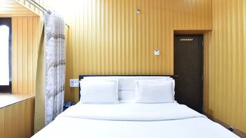 Quarto de hotel com uma cama grande, parede de madeira, uma porta e uma janela.