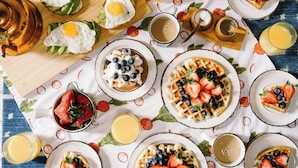 A breakfast setting with various dishes like eggs, waffles, and fruit.