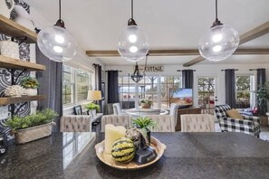 Un salon spacieux avec une grande table ronde, des sièges confortables et un éclairage suspendu.