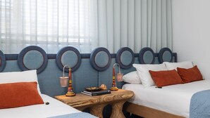 Una habitación de hotel con dos camas, una mesita de noche de madera y un cabecero con espejos circulares.