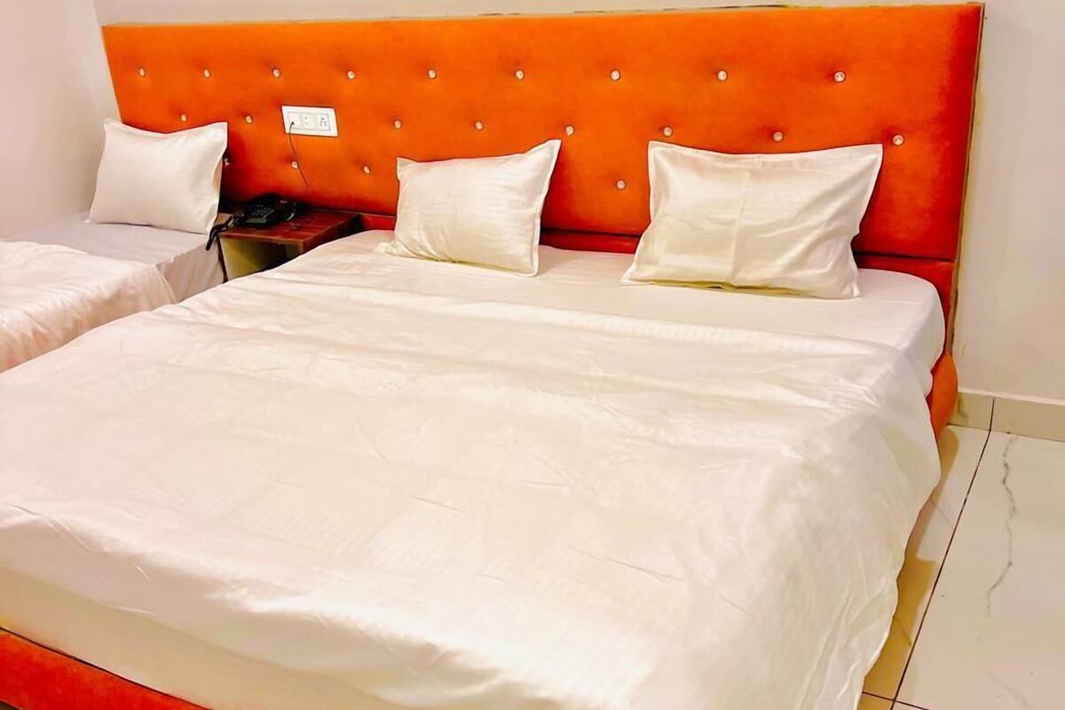 A double bed with a red upholstered headboard and white bedding.