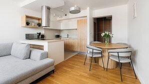 Una cucina moderna con piano cottura integrato, forno a microonde e macchina del caffè. C'è una zona pranzo con un tavolo rotondo e quattro sedie.