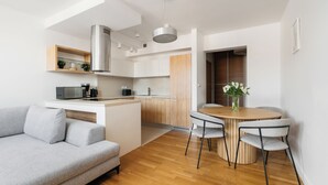 Eine moderne Küche mit Kochinsel, einem Essbereich mit rundem Tisch und Stühlen sowie einem grauen Sofa.