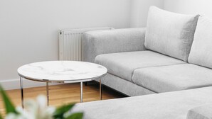 Ein modernes Wohnzimmer mit einem grauen Sofa, einem runden Couchtisch und einem kleinen Beistelltisch.