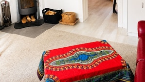 A living room with a fireplace, a television, and a red patterned rug.