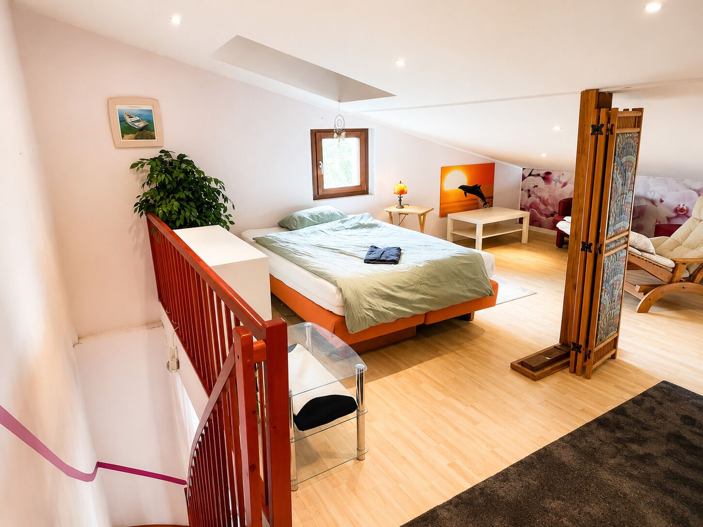 Un dormitorio moderno con cama, mesita de noche, lámpara, silla y vistas al exterior.
