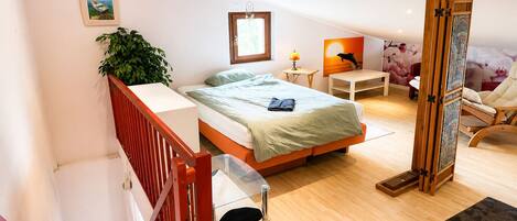 Un dormitorio moderno con cama, mesita de noche, lámpara, silla y vistas al exterior.