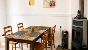 A dining area with a wooden table and chairs, a fireplace, and two wall-mounted artworks.