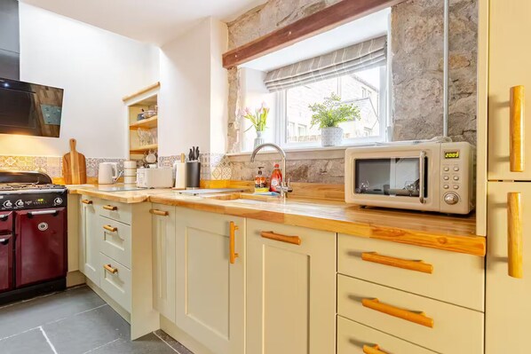 Una cocina con estufa, microondas, pileta y armarios de madera.