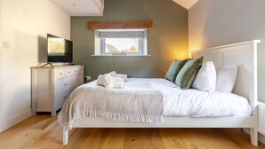 Une chambre à coucher avec un lit, une commode, un téléviseur et une fenêtre.