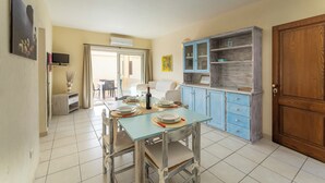 Een eetgedeelte met een tafel gedekt voor twee personen, een blauwe kast met glazen deuren en een houten deur.