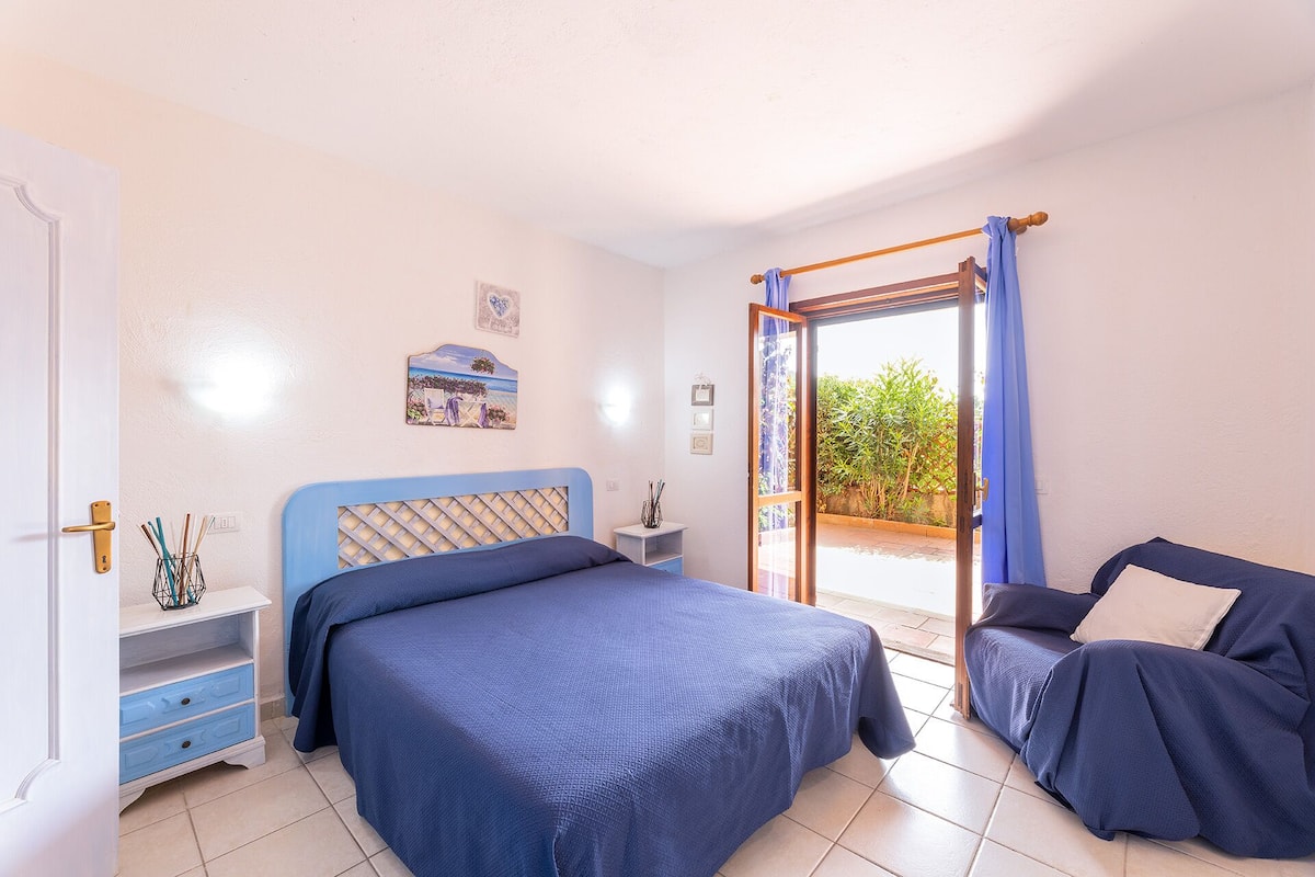 Une chambre à coucher comprenant un lit, une table de chevet, une commode, une chaise et une vue sur l’extérieur.