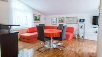 Een moderne woonkamer met een ronde tafel, rode banken en een televisie aan de muur.