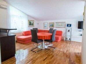 A modern living room with a round table, red sofas, and a TV on the wall.