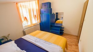 Une chambre à coucher avec un lit, une armoire, un bureau et une fenêtre avec des rideaux.