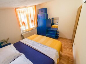 A bedroom with a bed, a wardrobe, a desk, and a window with curtains. - Apartments Galić (Ploce)