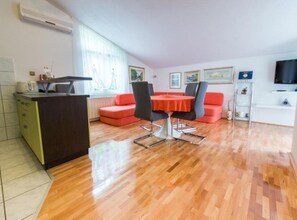 A modern living room with a dining area, a kitchen, and a TV. - Apartments Galić (Ploce)
