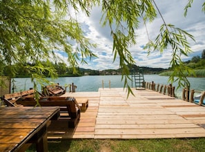 A wooden dock extending into a calm lake, surrounded by lush greenery and a clear sky. - Apartments Galić (Ploce)