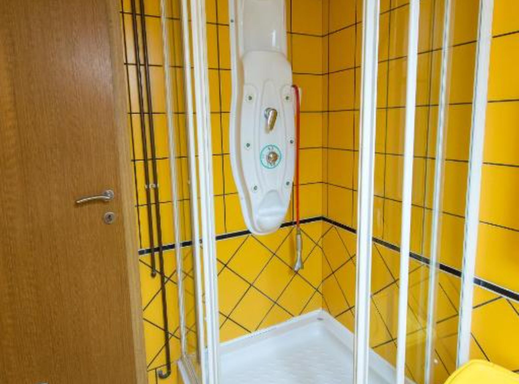 A bathroom with yellow tiled walls, a white toilet, and a wooden door.