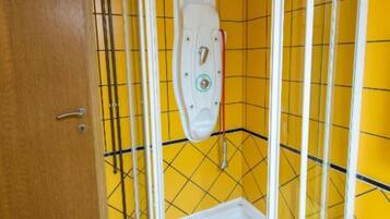A bathroom with yellow tiled walls, a white toilet, and a wooden door.