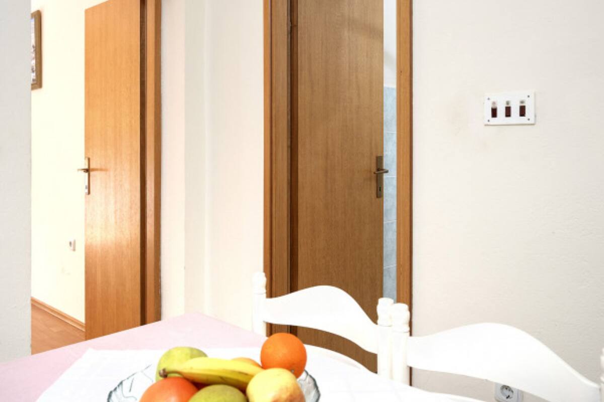 Una camera da letto con un letto, un comodino con una ciotola di frutta e due porte in legno.