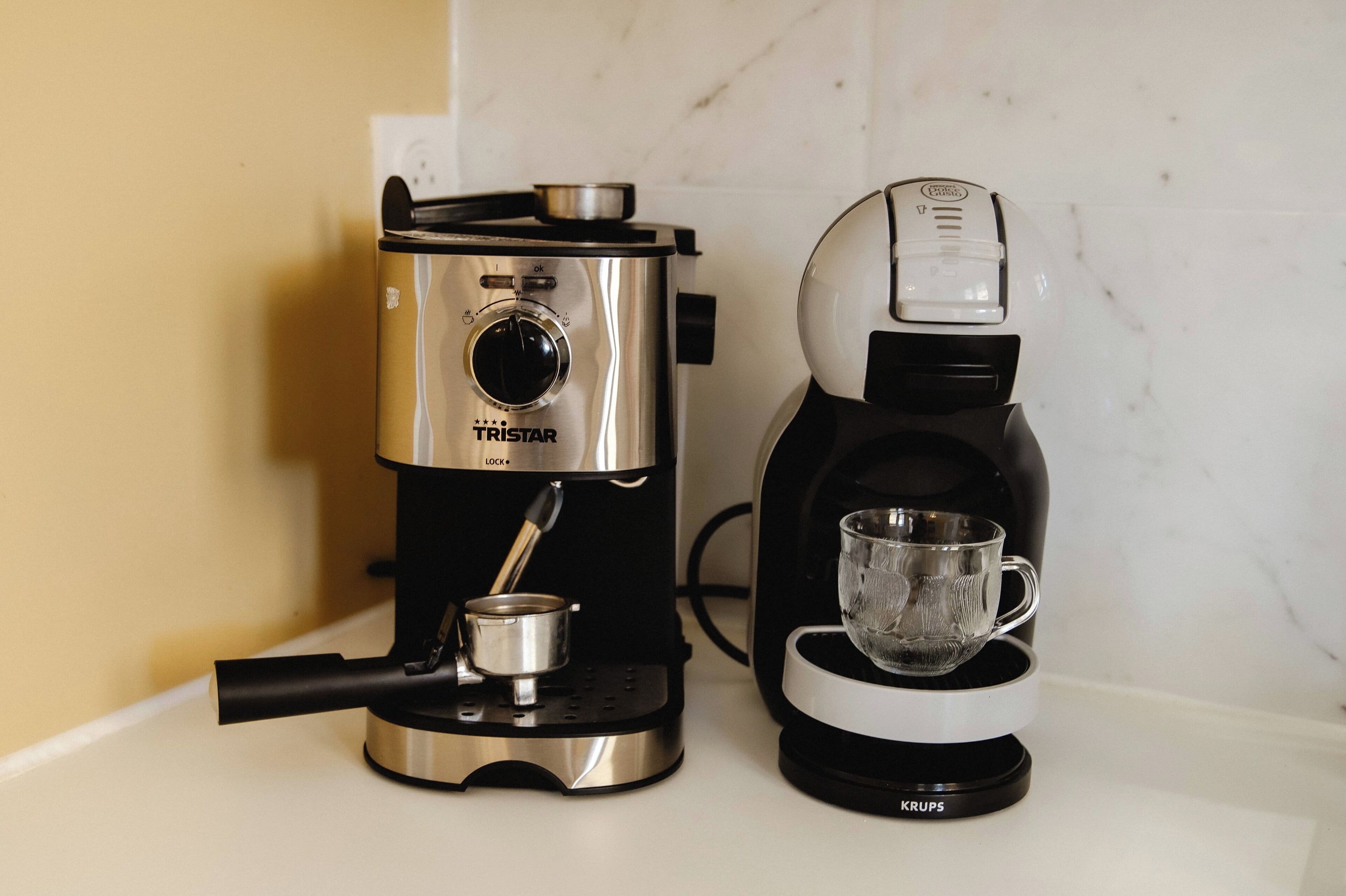 Two coffee makers, one labeled 'TRISTAR' and the other 'KRUPS', placed on a countertop.