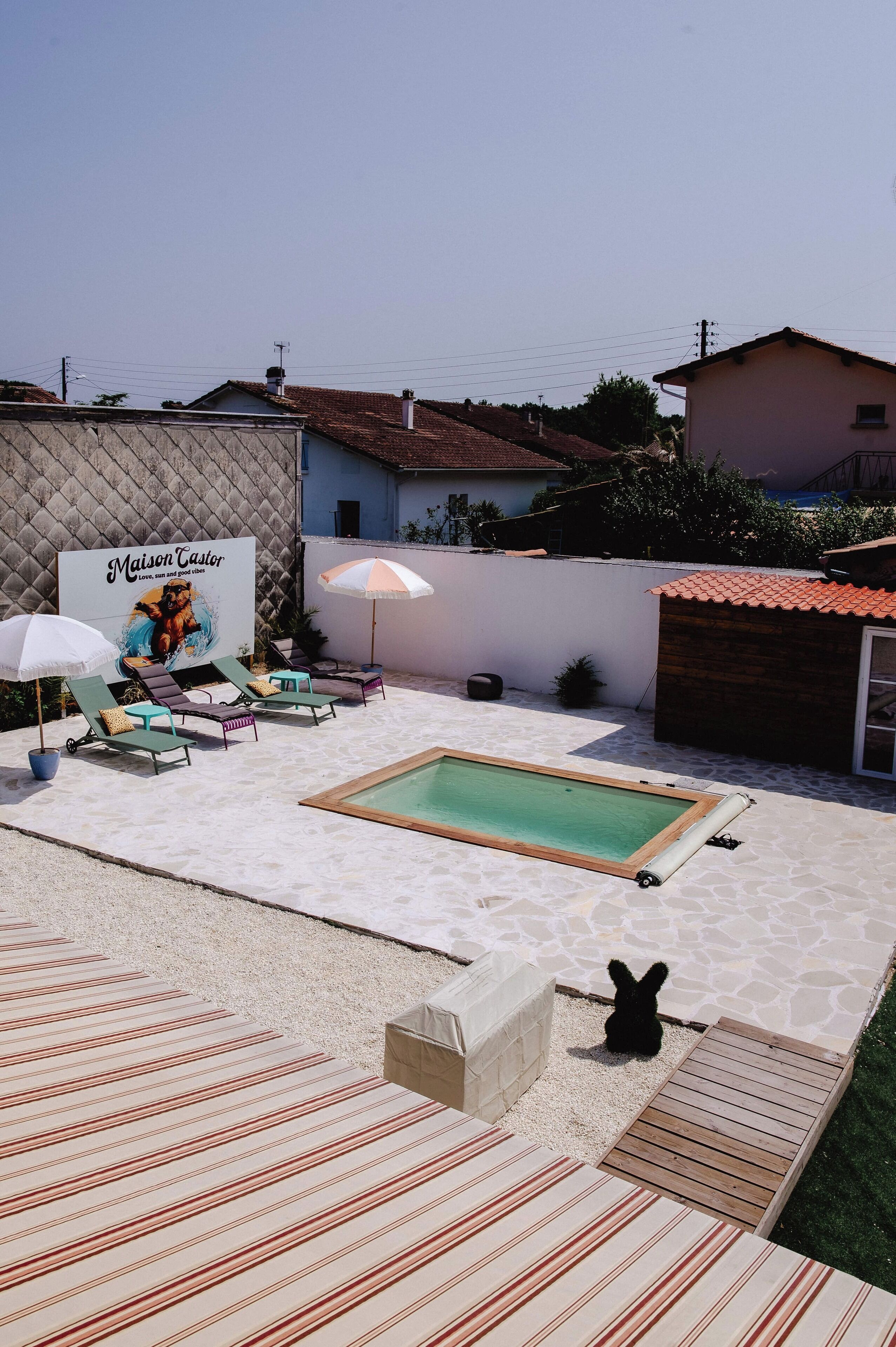Ein Garten mit Swimmingpool, Liegestühlen und einem Schild für Maison Castor.