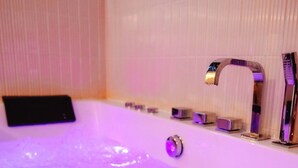 A bathtub with a purple light, a handheld showerhead, and a control panel. - *Maison Castor* Balneo, pool and billiards! 10 minutes from the ocean! (Mimizan)