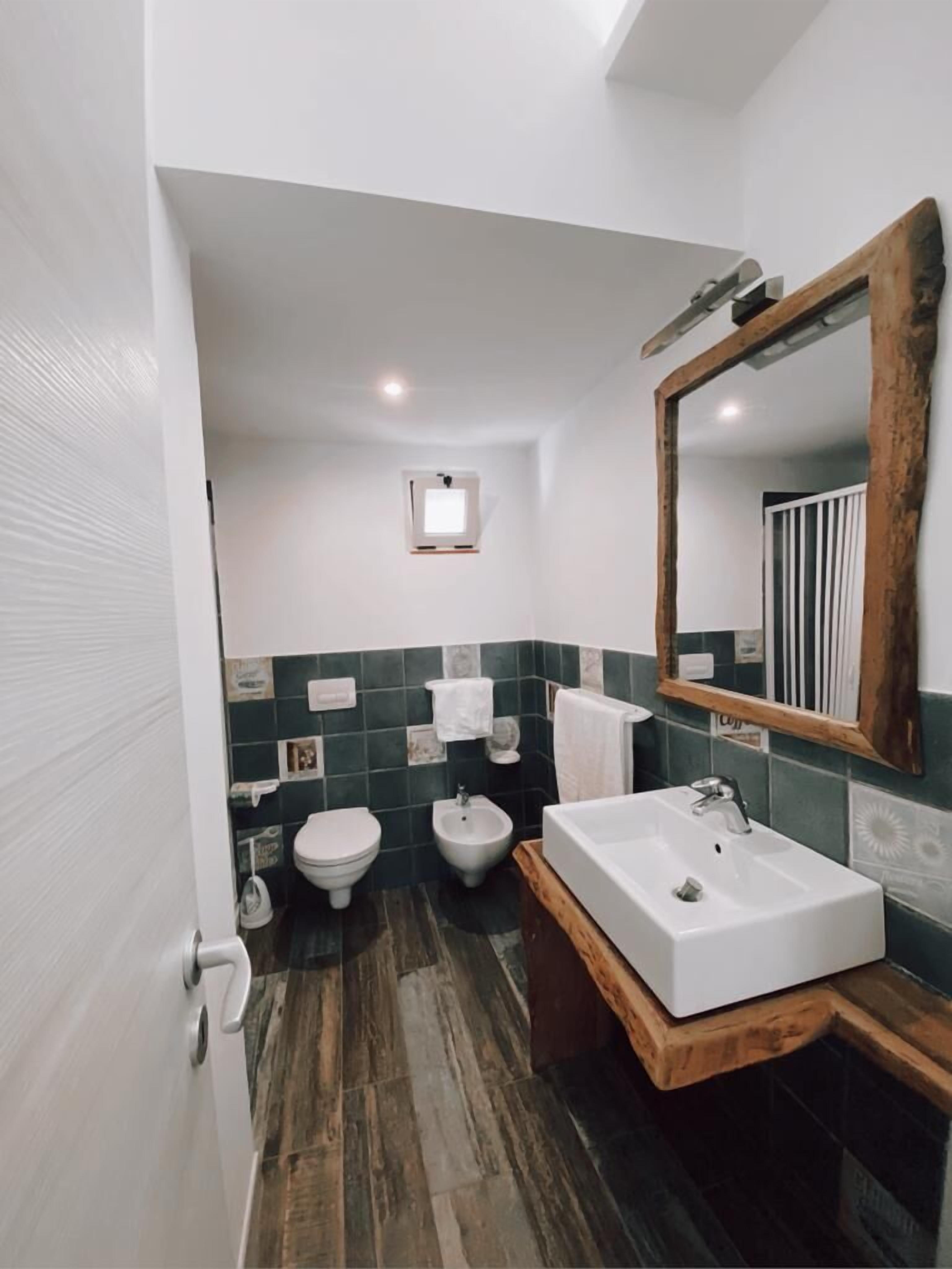 Une salle de bain avec un meuble-lavabo en bois, un lavabo blanc, un bidet et des toilettes.