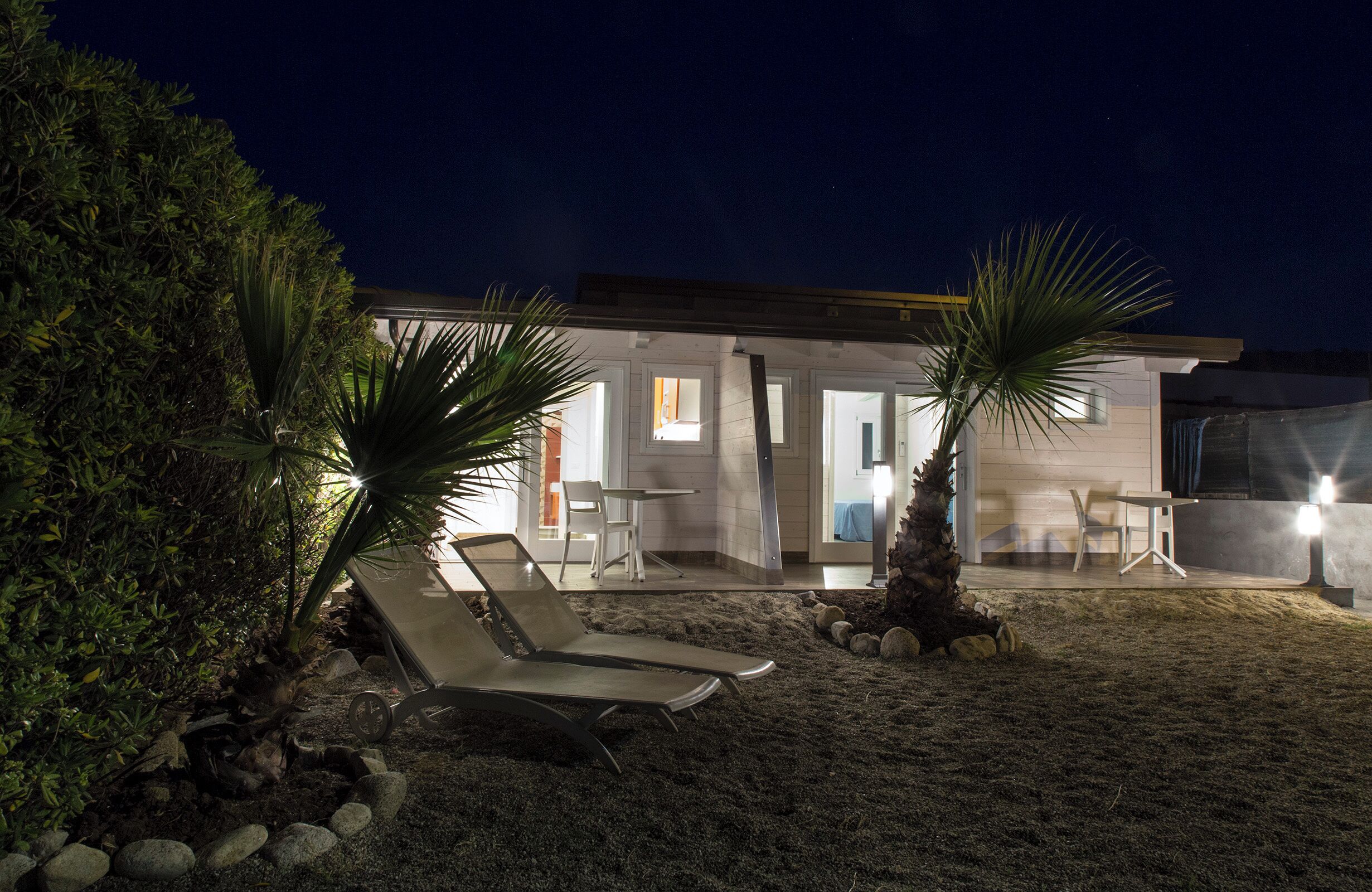 A modern house with a patio area featuring a lounge chair and a small table.