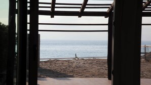 Eine offene Holzkonstruktion mit Blick auf einen Strand und das Meer.