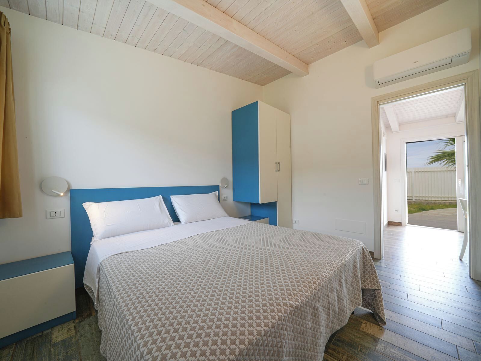 Un dormitorio con cama, armario y puerta que da a un espacio exterior.