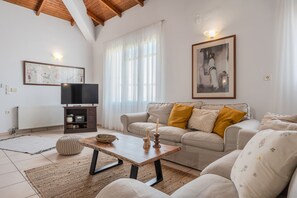 A living room with a sofa, a coffee table, a TV, and a framed picture on the wall. - Galini villa, private pool , near amenities, Heraklion (Episkopi)