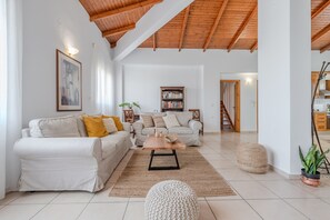 A spacious living room with a high wooden ceiling, a large bookshelf, and a cozy seating area with two sofas and a coffee table. - Galini villa, private pool , near amenities, Heraklion (Episkopi)