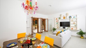 A dining area with a wooden table set for a meal, a colorful chandelier, and a white sofa in the background. - VILLA LEONARDO IN THE HEART OF POSITANO Central location (Positano)
