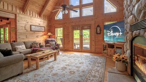A cozy log cabin interior with a fireplace, a television, and a comfortable seating area. - My Happy Place - Lakefront cabin (New Tazewell)