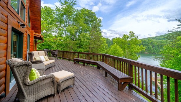 A wooden deck with wicker furniture and a view of a river. - My Happy Place - Lakefront cabin (New Tazewell)