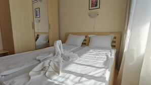 Un letto rifatto con lenzuola bianche e un asciugamano piegato.