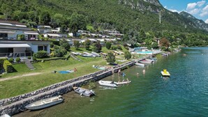 A lakeside resort with villas, a dock with boats, and a mountainous backdrop. - Directly on the lake with terrace (Tre Capitelli)