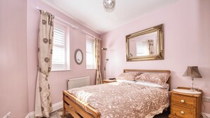 A bedroom with a wooden bed, a nightstand, a lamp, and a mirror on the wall. - Beach, Dreamland, Restaurants Nearby- Sunny Garden (Margate)