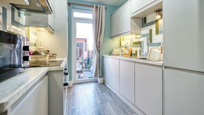 A modern kitchen with white cabinets, a marble countertop, and a view to the outside. - Beach, Dreamland, Restaurants Nearby- Sunny Garden (Margate)