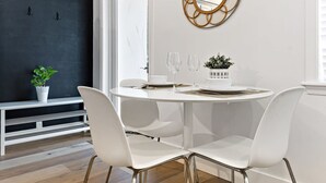A modern dining area with a round table, white chairs, and a decorative mirror on the wall.