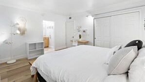 A bedroom with a large bed, a bedside table, a desk, and a wardrobe.
