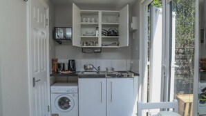A compact kitchen with a built-in washing machine, a sink, and a window providing natural light.