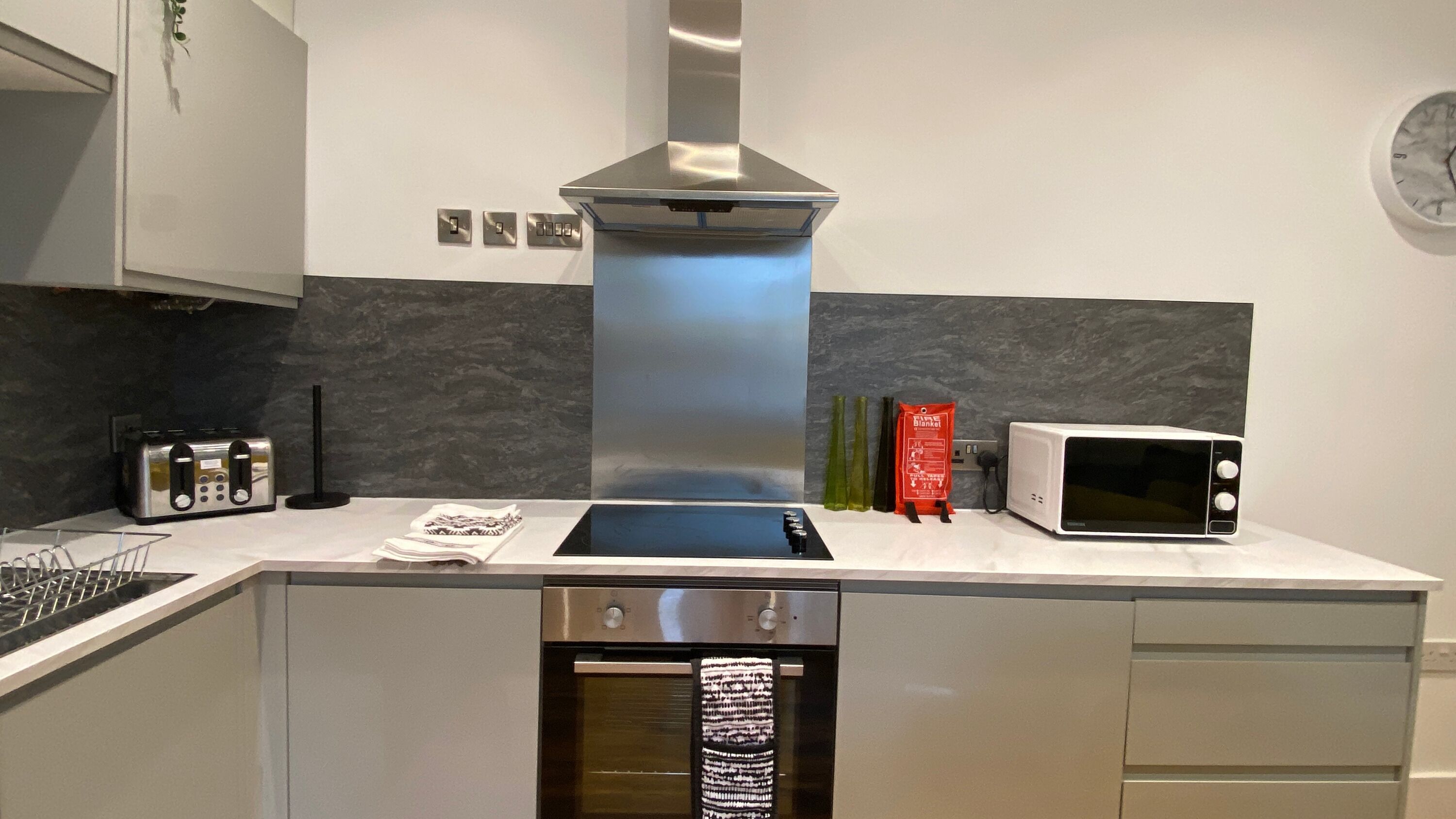 A modern kitchen with a stainless steel range hood, a built-in microwave, and a dishwasher.