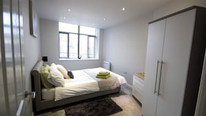 A bedroom with a bed, a window, a wardrobe, and a small desk. - Stayzo Self Catering Accommodation 3 -bradford UK (Bradford)
