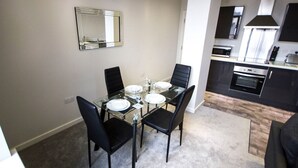 A dining area with a glass table, black chairs, and a mirror on the wall. - Stayzo Self Catering Accommodation 3 -bradford UK (Bradford)