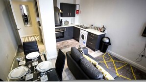 A compact living space with a dining area, sofa, kitchen, and laundry area. - Stayzo Self Catering Accommodation 3 -bradford UK (Bradford)